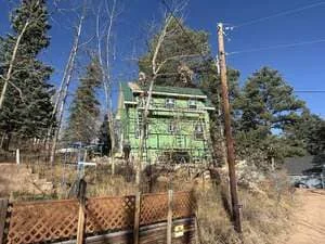Two-story home under construction with green board-and-batten siding and exposed framing