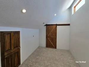 Interior room with white drywall, recessed lighting, concrete floor, and two dark wooden barn doors