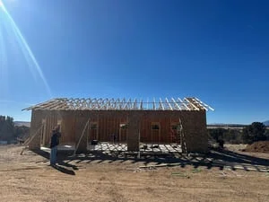 Wood-framed residential structure with metal roof trusses and standing seam roofing installation