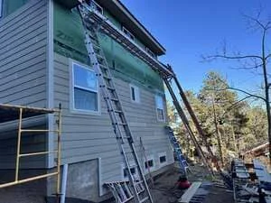 Fiber cement siding installation on residential home exterior with ladder access