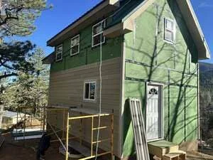Home exterior with new fiber cement siding, windows, and door installation in progress