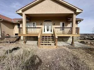 Elevated home addition with wooden deck stairs, covered porch, and concrete foundation pilings