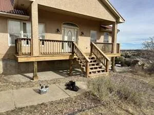 Pressure-treated wood deck with railings attached to residential home exterior