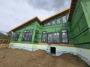 Green board-and-batten siding addition with wood trim and new window installation
