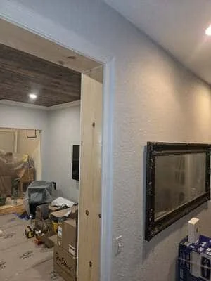 Interior drywall installation with framed doorway, recessed lighting, and TV mounting preparation