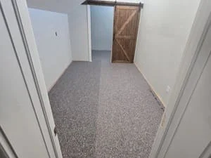 Gray carpet flooring installed in hallway with white walls and door frames