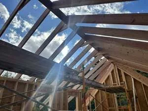 Wooden beam framing with installed skylights allowing natural light into interior space