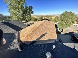 New asphalt shingle roof installation on residential home with clear blue sky
