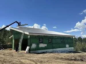 Green metal siding residential addition with new roofing and framing during construction