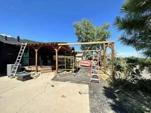Wooden pergola frame with timber beams under construction on concrete patio