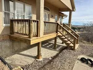 Elevated wood deck with turned balusters, stairs, and covered entry attached to residential home